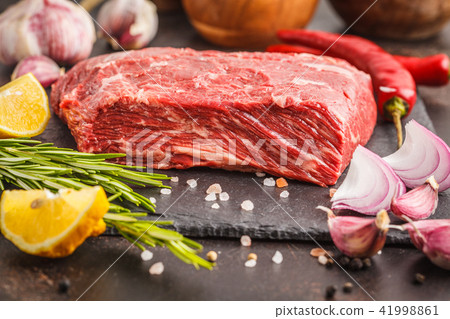 Raw whole piece of beef on slate with spices 41998861