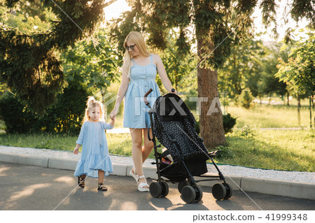 little daughter helps mom push the baby carriage little daughter helps mom push the baby carriage 41999348