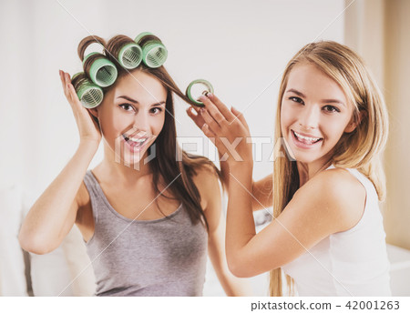 Beautiful Girl Helps Girlfriend to Curl Hair. 42001263