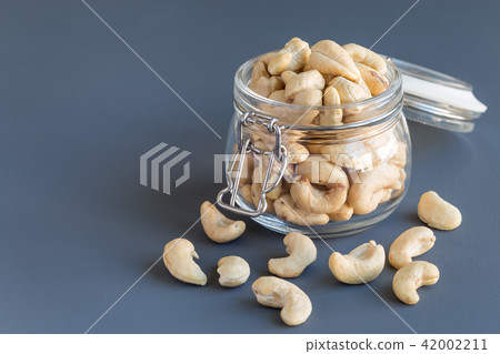 Cashew nuts in glass jar on concrete background 42002211