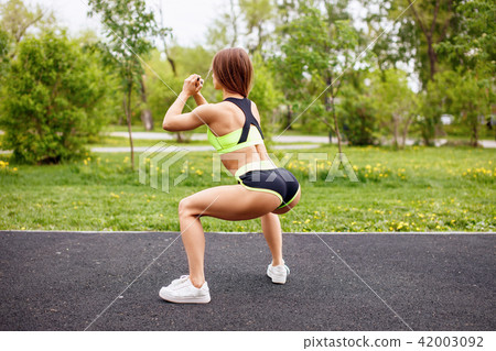 Sport girl in sportswear doing squatting in the park. 42003092