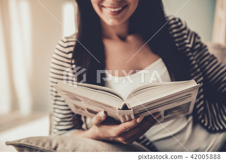 Close up. Young Smiling Woman Reading Book at Home 42005888