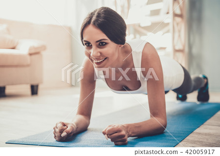 Young Smiling Woman Doing Exercises on Mat at Home Young Smiling Woman Doing Exercises on Mat at Home 42005917