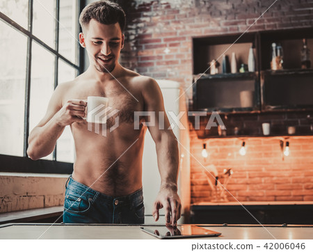 Bare-chested Man Using Tablet and Drink Coffee. Bare-chested Man Using Tablet and Drink Coffee. 42006046