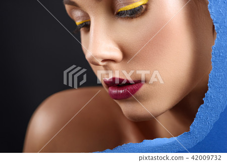 Contrast close up of young model posing with blue saturated cardboard. Contrast close up of young model posing with blue saturated cardboard. 42009732