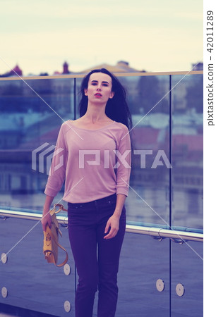 Pretty young woman posing near a glass wall Pretty young woman posing near a glass wall 42011289
