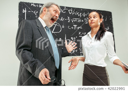 Male professor and young woman against chalkboard in classroom Male professor and young woman against chalkboard in classroom 42022991