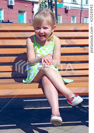 Little girl laughing while sitting on bench 42026943
