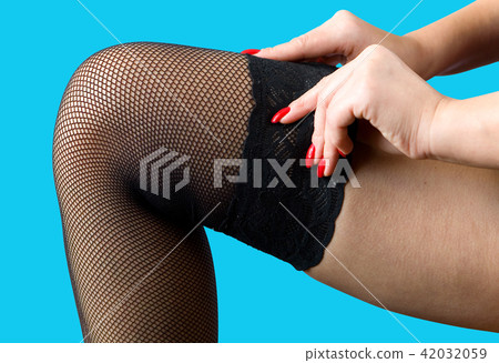 A woman pulls a stocking on her leg. A woman pulls a stocking on her leg. 42032059