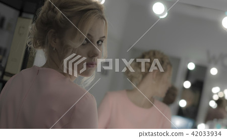 Beautiful girl with professional makeup look at camera reflected at mirror 42033934