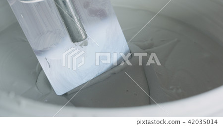 closeup worker dipping the trowel into the decorative concrete plaster 42035014