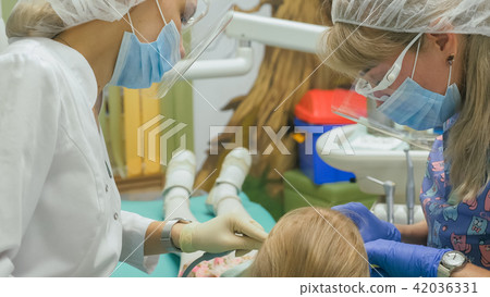 Child with a mother at a dentist's reception. The girl lies in the chair, behind her mother. The Child with a mother at a dentist's reception. The girl lies in the chair, behind her mother. The 42036331