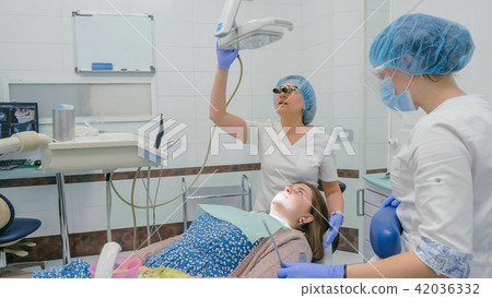 Woman at dentist clinic gets dental treatment to fill a cavity in a tooth. Dental restoration and Woman at dentist clinic gets dental treatment to fill a cavity in a tooth. Dental restoration and 42036332