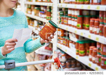 Woman chooses lecho tomato at grocery store Woman chooses lecho tomato at grocery store 42038691