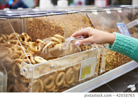 Woman in shop buys bagels with poppy using scoop 42038763