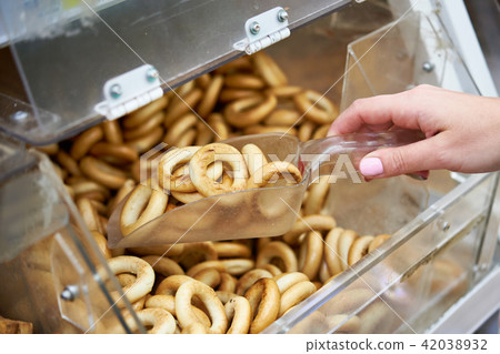 Woman in shop buys bagels using scoop for products 42038932