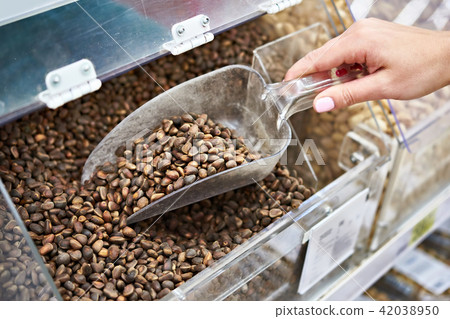 Buyer with scoop takes pine nuts in store Buyer with scoop takes pine nuts in store 42038950