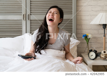 female sitting in the bed and burst into laughter female sitting in the bed and burst into laughter 42042995