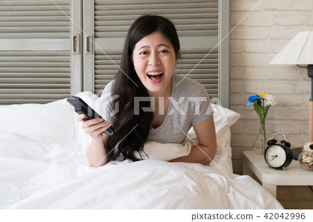 female sitting in the bed keep laughing female sitting in the bed keep laughing 42042996