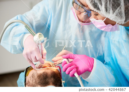 Close-up of dentist and her assistant working with patient teeth Close-up of dentist and her assistant working with patient teeth 42044867