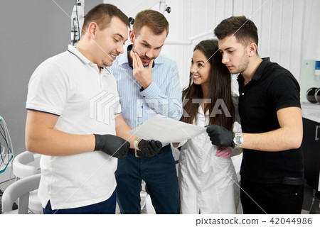 Dentist and his assistant show patients instructions for dental care Dentist and his assistant show patients instructions for dental care 42044986