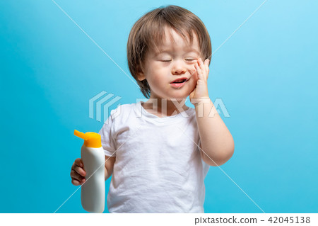 Toddler boy with a bottle of sunblock 42045138