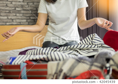Woman trying to fit all clothing to suitacase, girl starting pac Woman trying to fit all clothing to suitacase, girl starting pac 42045439