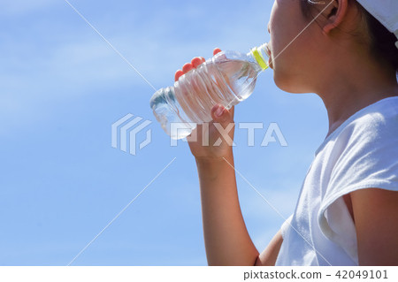A woman drinking water in a park A woman drinking water in a park 42049101