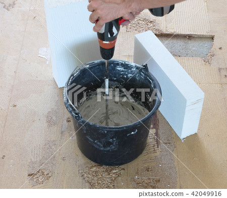Man is mixing grey concrete and prime  42049916