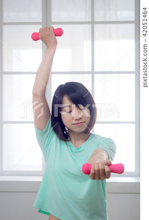 Young girl lifting dumbbells  42051464