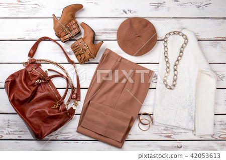 Women's wardrobe in bright beige wooden desks surface background. Women's wardrobe in bright beige wooden desks surface background. 42053613