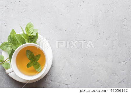 Cup of tea with fresh mint leaves on grey concrete 42056152