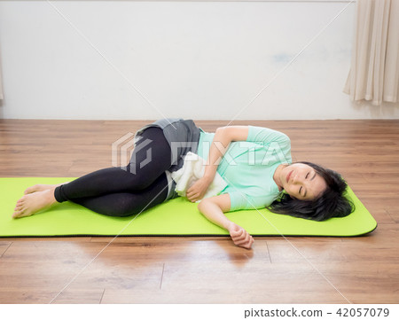 Young woman practicing yoga, lying on green mat. 42057079