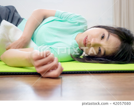 Young woman practicing yoga, lying on green mat. 42057080
