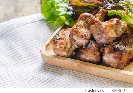 Fired pork rips on wooden plate with vegetable. 42061264