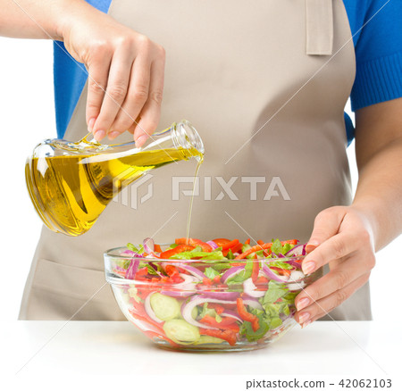 Cook is pouring olive oil into salad Cook is pouring olive oil into salad 42062103
