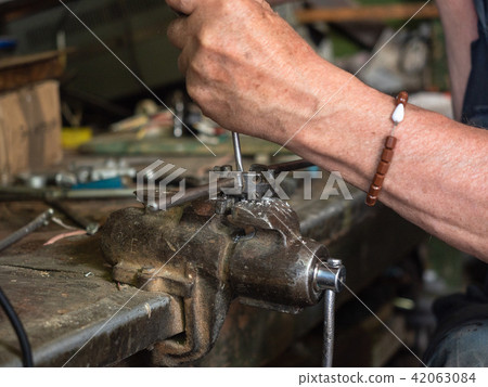 Threading die vised in iron grip by worker's hands 42063084