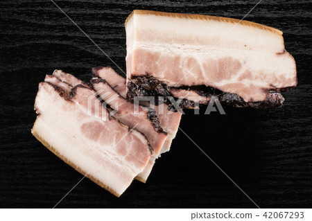 Fresh smoked english bacon on black wood Fresh smoked english bacon on black wood 42067293
