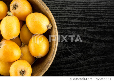 Fresh raw orange japanese loquat on black wood 42068485
