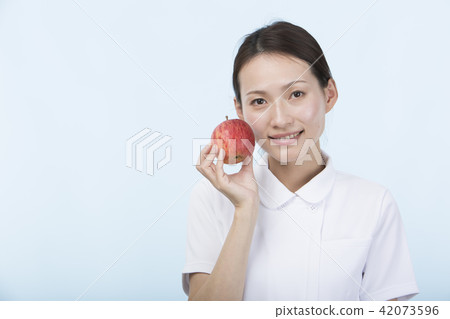 A woman in a white suit smiling with an apple A woman in a white suit smiling with an apple 42073596