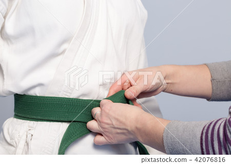 Hands of a parent who helps a child to tie a belt 42076816