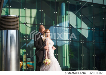bride and groom holding each other near futuristic building 42080465