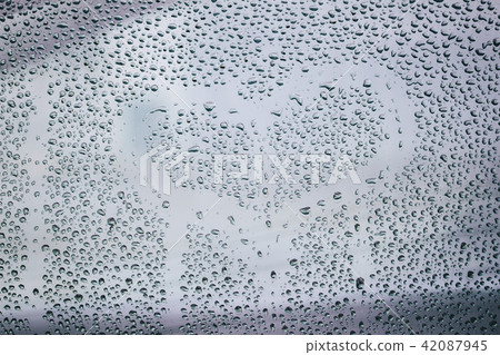 Heart and raindrops. Drawn romantic blurred love symbol drawn by hand on the wet window glass, light Heart and raindrops. Drawn romantic blurred love symbol drawn by hand on the wet window glass, light 42087945
