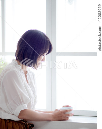 woman standing in front of window and drink coffee woman standing in front of window and drink coffee 42088969