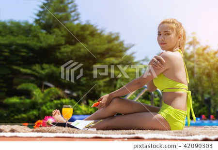 Beautiful girl in swimsuit is wearing a sunblock Beautiful girl in swimsuit is wearing a sunblock 42090303
