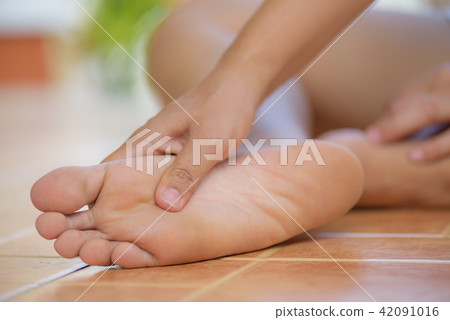 Woman feeling pain in her foot at home. Woman feeling pain in her foot at home. 42091016