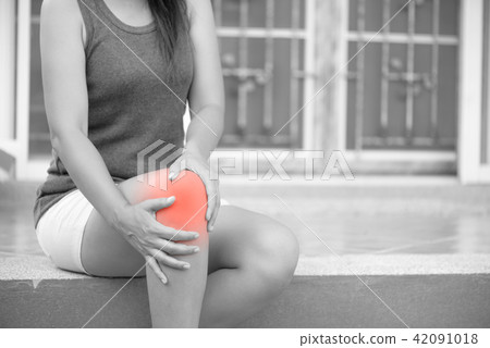 Woman feeling pain in her knee at home Woman feeling pain in her knee at home 42091018