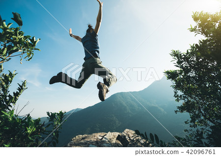 successful hiker jumping on sunrise mountain top successful hiker jumping on sunrise mountain top 42096761