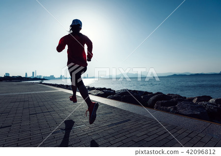 young fitness woman running on sunrise seaside 42096812