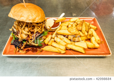 Home made hamburger with lettuce, cheese, beef meat and french fries placed on stainless steel table Home made hamburger with lettuce, cheese, beef meat and french fries placed on stainless steel table 42098684